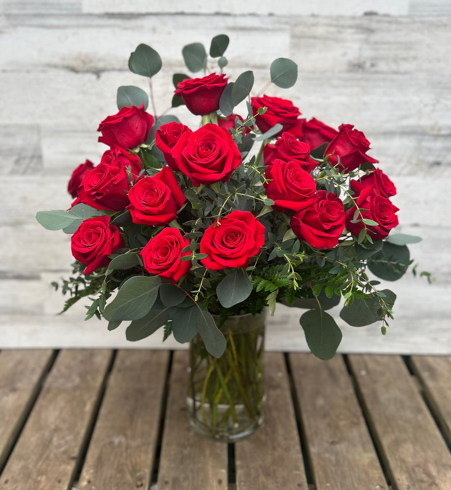 Two Dozen Long Stem Red Roses with Exotic Greens in a Vase